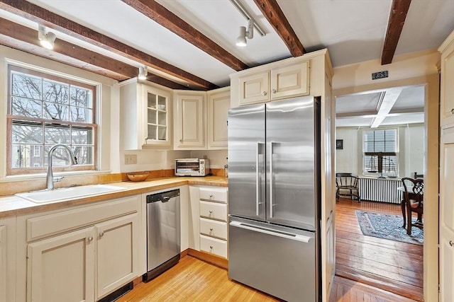 kitchen featuring sink, stainless steel appliances, cream cabinetry, and light wood-type flooring