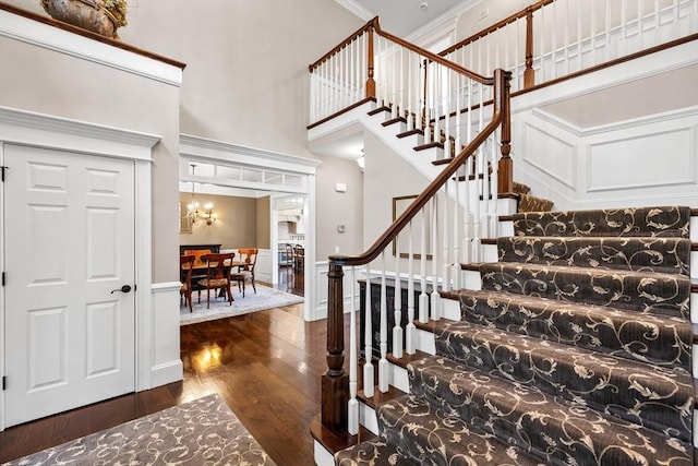 33 Old Concord Rd, Lincoln, MA 01773 - staircase with crown molding, a decorative wall, a wainscoted wall, wood finished floors, and a towering ceiling