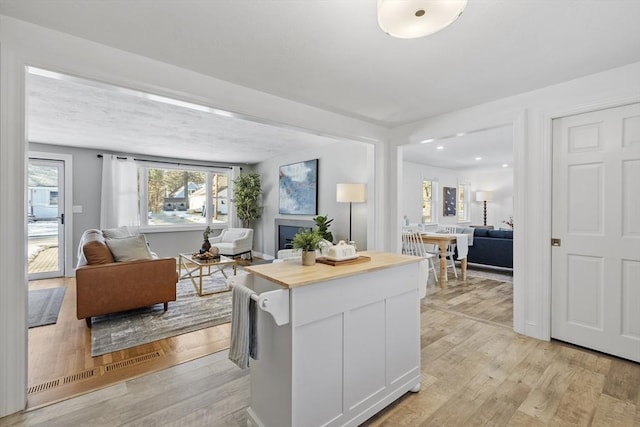 kitchen with white cabinets, butcher block countertops, and light hardwood / wood-style floors