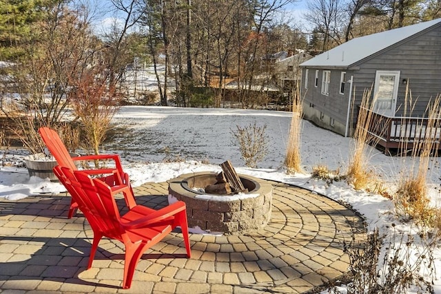 snow covered patio with an outdoor fire pit