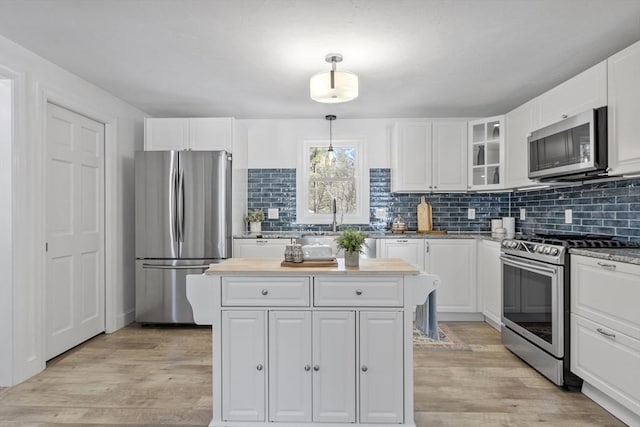 kitchen with white cabinets, hanging light fixtures, and appliances with stainless steel finishes