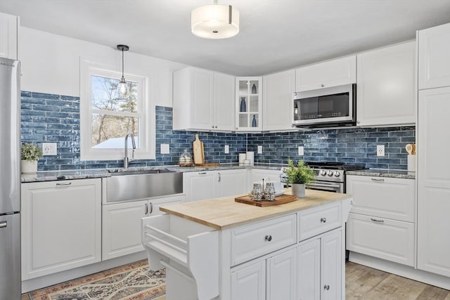 kitchen featuring stainless steel appliances, white cabinets, tasteful backsplash, and pendant lighting