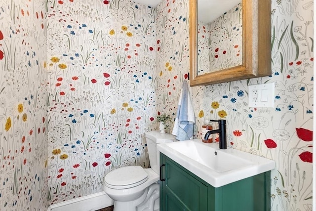 bathroom with toilet, wallpapered walls, and vanity