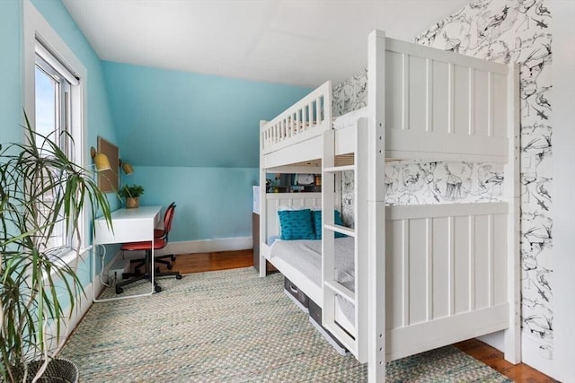 bedroom with lofted ceiling, baseboards, and wood finished floors