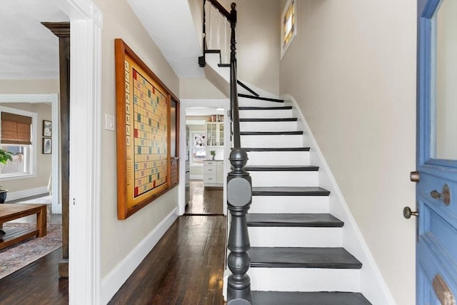 stairway featuring a wealth of natural light, baseboards, and wood finished floors