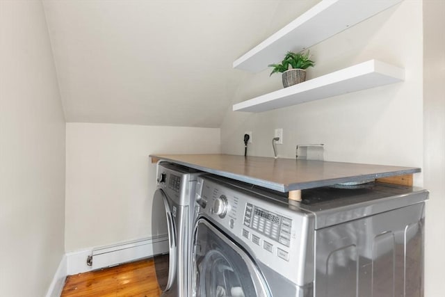 washroom with a baseboard heating unit, laundry area, wood finished floors, baseboards, and washing machine and clothes dryer