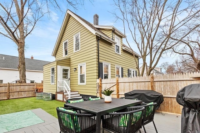 back of house featuring entry steps, a fenced backyard, a chimney, a wooden deck, and outdoor dining space