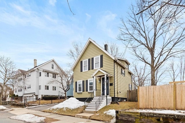 view of front of home with a chimney and fence