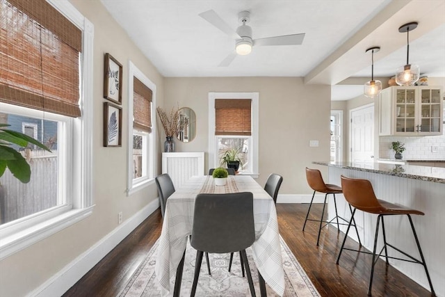 dining area featuring a ceiling fan, baseboards, and dark wood-type flooring