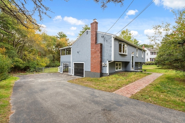 view of side of property featuring a garage and a lawn