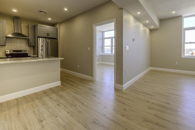 kitchen with wall chimney exhaust hood, appliances with stainless steel finishes, visible vents, and a healthy amount of sunlight