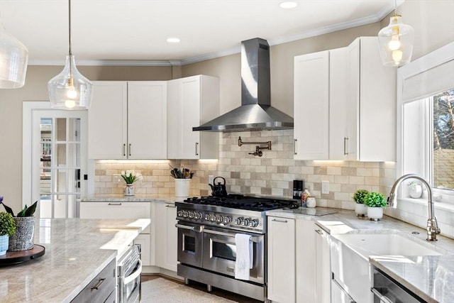 kitchen with appliances with stainless steel finishes, white cabinets, light stone counters, and wall chimney exhaust hood