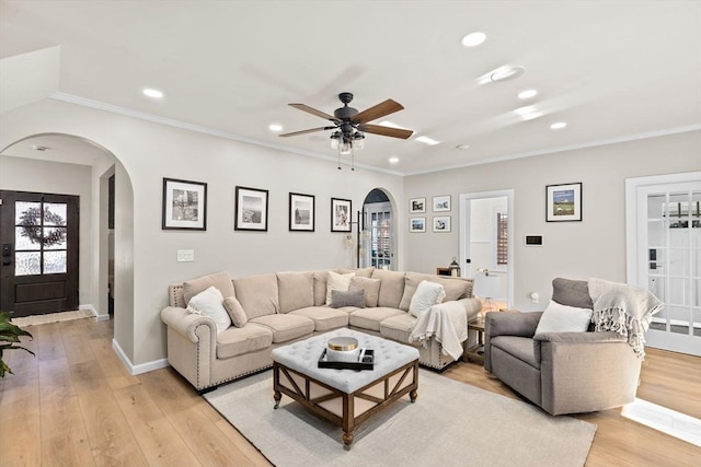 living room with ceiling fan, ornamental molding, and light hardwood / wood-style flooring