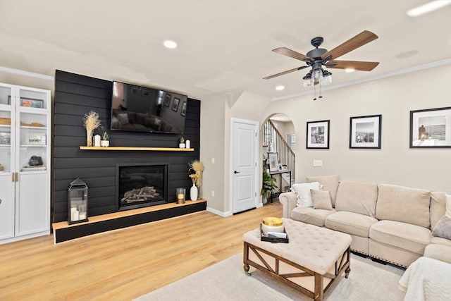 living room with crown molding, ceiling fan, and light wood-type flooring