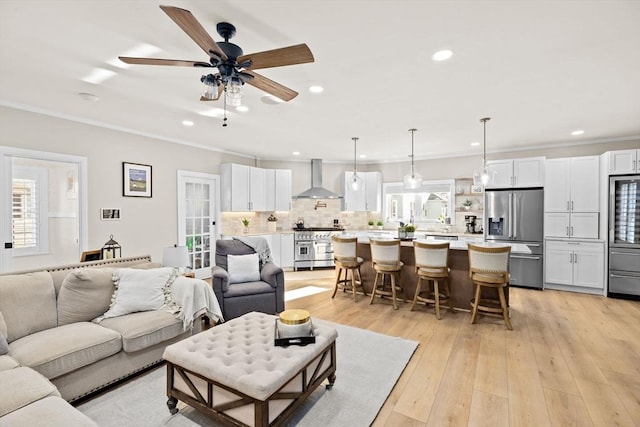 living room featuring crown molding, a healthy amount of sunlight, and light wood-type flooring