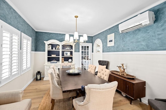 dining area featuring light hardwood / wood-style flooring, ornamental molding, a wall unit AC, and an inviting chandelier