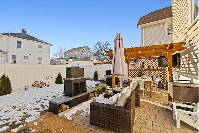 snow covered patio with exterior fireplace and a pergola