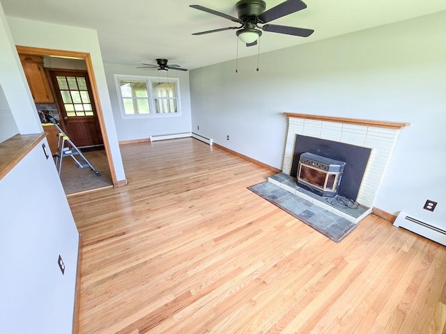 264 Dresser Hill Rd, Dudley, MA 01571 - unfurnished living room featuring wood finished floors, a baseboard heating unit, ceiling fan, baseboards, and a wood stove