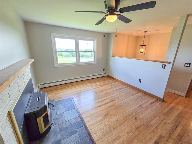 264 Dresser Hill Rd, Dudley, MA 01571 - unfurnished living room featuring baseboard heating, a wood stove, wood finished floors, a ceiling fan, and baseboards