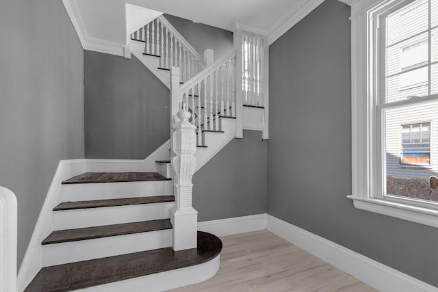 stairway featuring crown molding, baseboards, a wealth of natural light, and wood finished floors