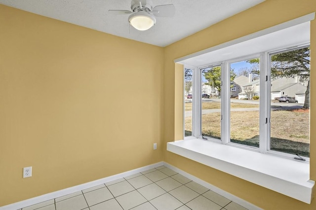 spare room with light tile patterned floors, baseboards, and ceiling fan