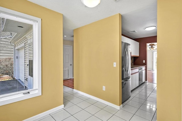 kitchen featuring light tile patterned floors, a healthy amount of sunlight, white cabinetry, and stainless steel appliances