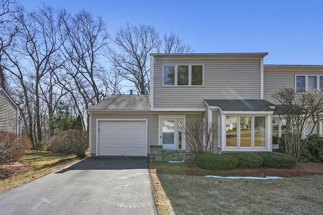 view of front of home with a garage, stone siding, and aphalt driveway