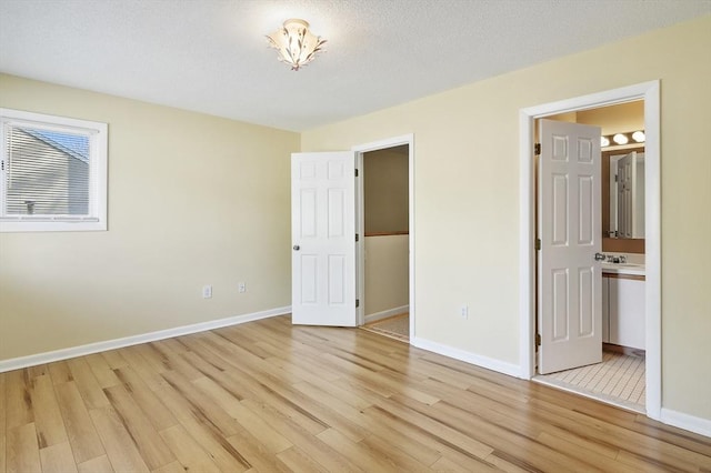 unfurnished bedroom with baseboards, light wood-style floors, and a textured ceiling