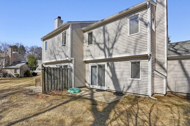 rear view of house with a yard, a chimney, and a patio area