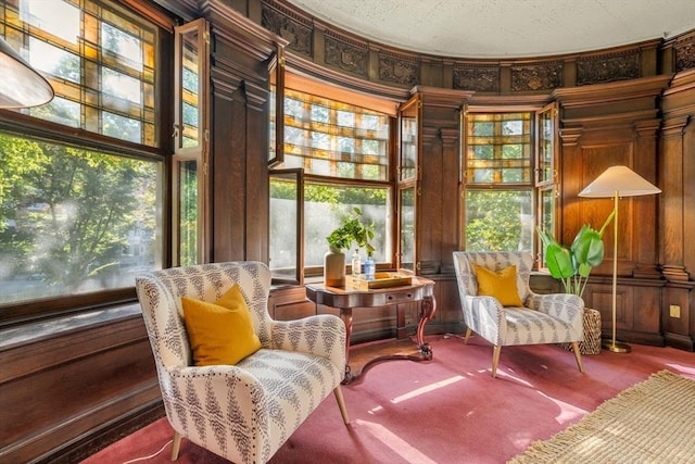 living area with carpet floors and wooden walls