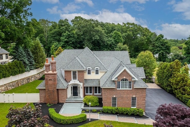 view of front facade with fence private yard, a front lawn, a chimney, and brick siding