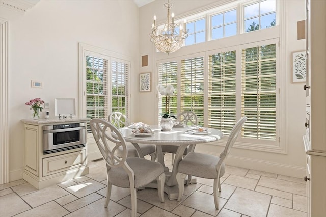 dining space featuring an inviting chandelier, baseboards, and a high ceiling