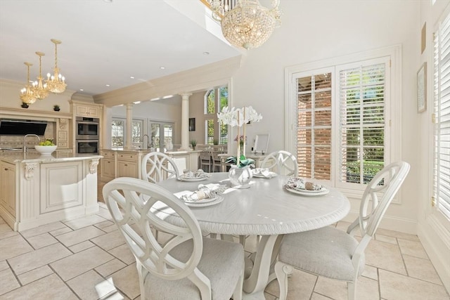 dining area with baseboards, decorative columns, a chandelier, and stone tile flooring