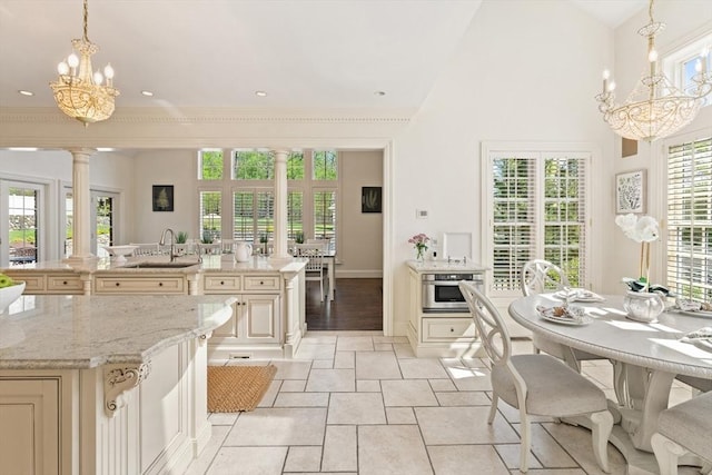 kitchen featuring a sink, cream cabinets, decorative columns, and a chandelier