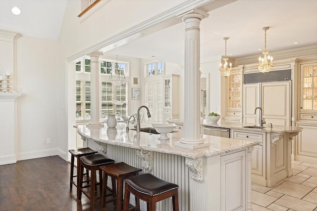 kitchen featuring a sink, paneled refrigerator, an island with sink, and a kitchen breakfast bar
