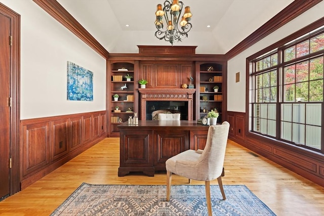 office with an inviting chandelier, wainscoting, light wood finished floors, a fireplace, and built in features