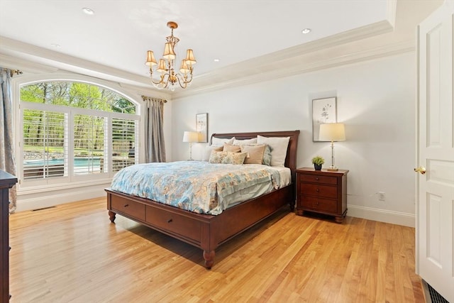 bedroom with light wood-style floors, baseboards, a tray ceiling, and a notable chandelier