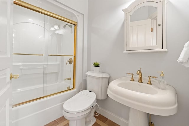 full bathroom with shower / bath combination with glass door, a sink, baseboards, and toilet