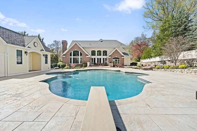 outdoor pool featuring a diving board and a patio area
