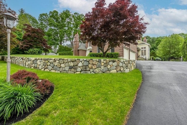 exterior space featuring a lawn, a garage, and aphalt driveway