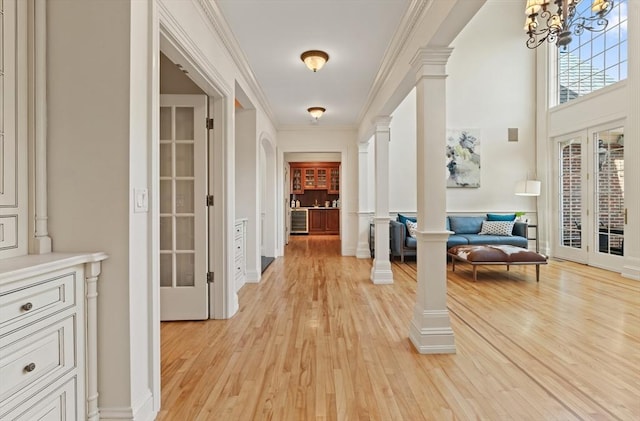 hall with crown molding, a notable chandelier, french doors, and light wood-style floors
