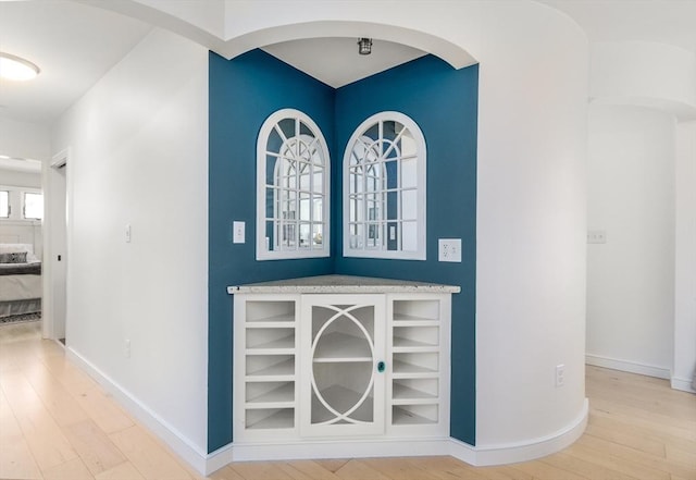 interior space featuring wood finished floors, baseboards, and arched walkways