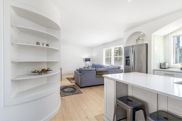 kitchen featuring light wood-style flooring, a breakfast bar area, stainless steel fridge, and white cabinets