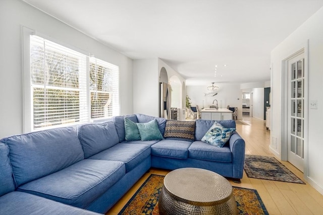 living area featuring arched walkways and light wood-type flooring