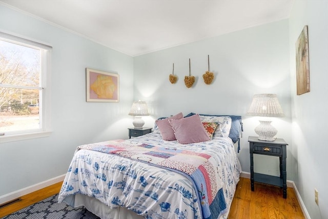 bedroom with visible vents, baseboards, and wood finished floors