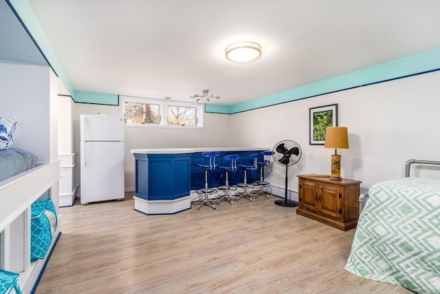 bedroom with light wood-style flooring, a dry bar, and freestanding refrigerator