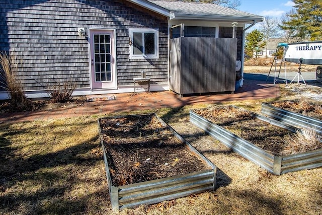 back of property with a garden and roof with shingles