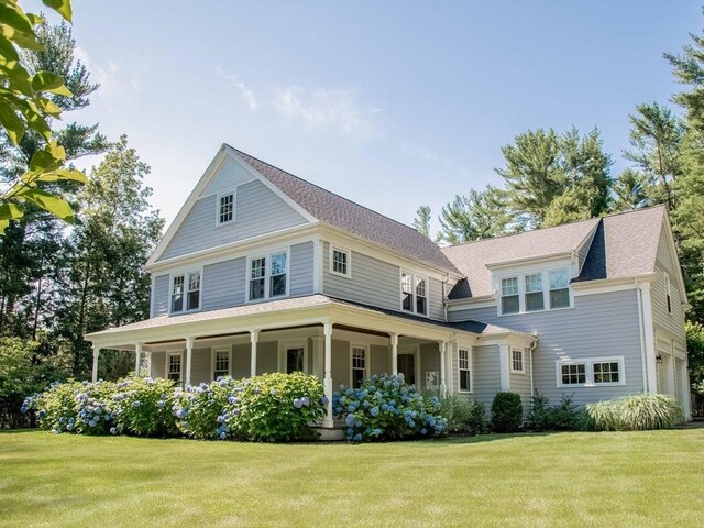 view of front facade featuring a garage, covered porch, and a front yard