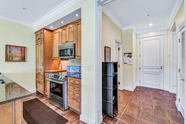 kitchen with dark stone countertops, backsplash, crown molding, and appliances with stainless steel finishes