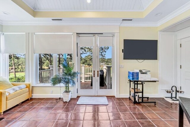 doorway with ornamental molding, a raised ceiling, and dark tile patterned flooring